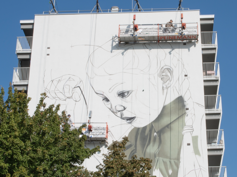 gomad mural muurschildering flat building geleen smug Graffiti artiest Smug aan het werk op hoogwerker tijdens groot mural project in Geleen