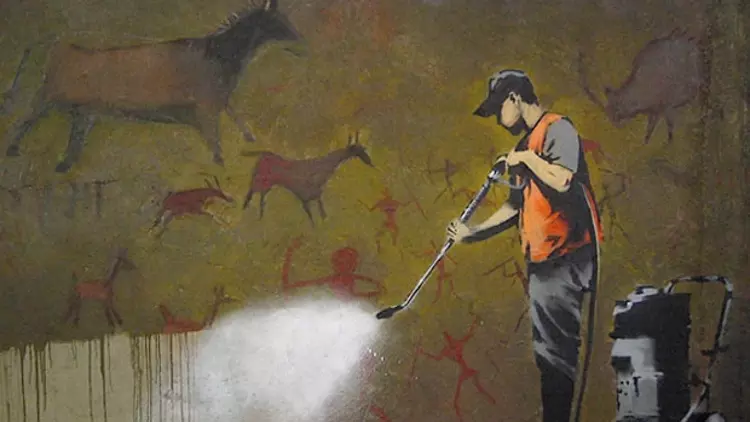Banksy die met een hoge drukspuit grottekeningen schoon spuit